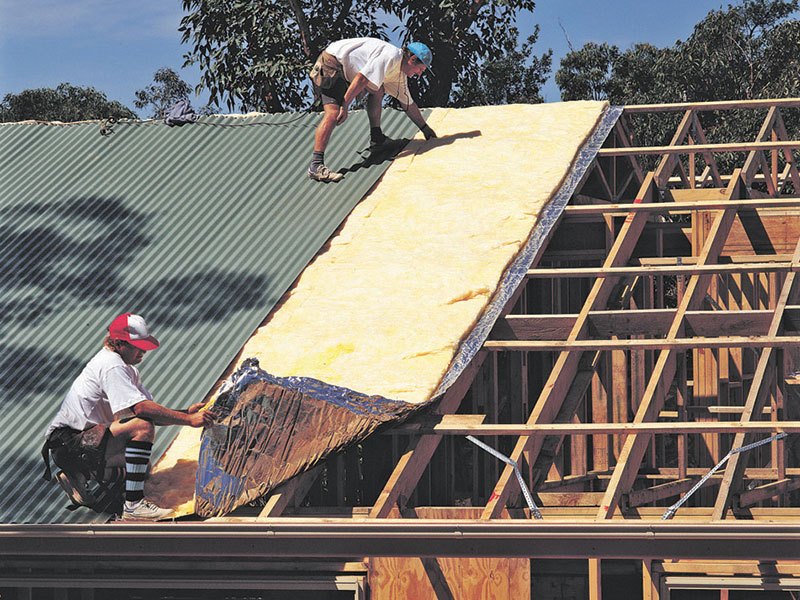 Two men installing insulation on a roof