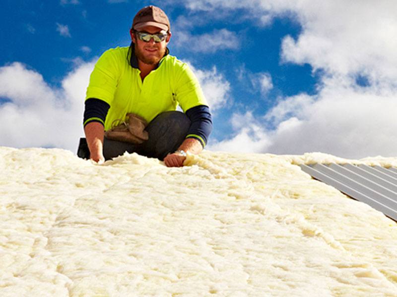 Man installing insulation on a roof